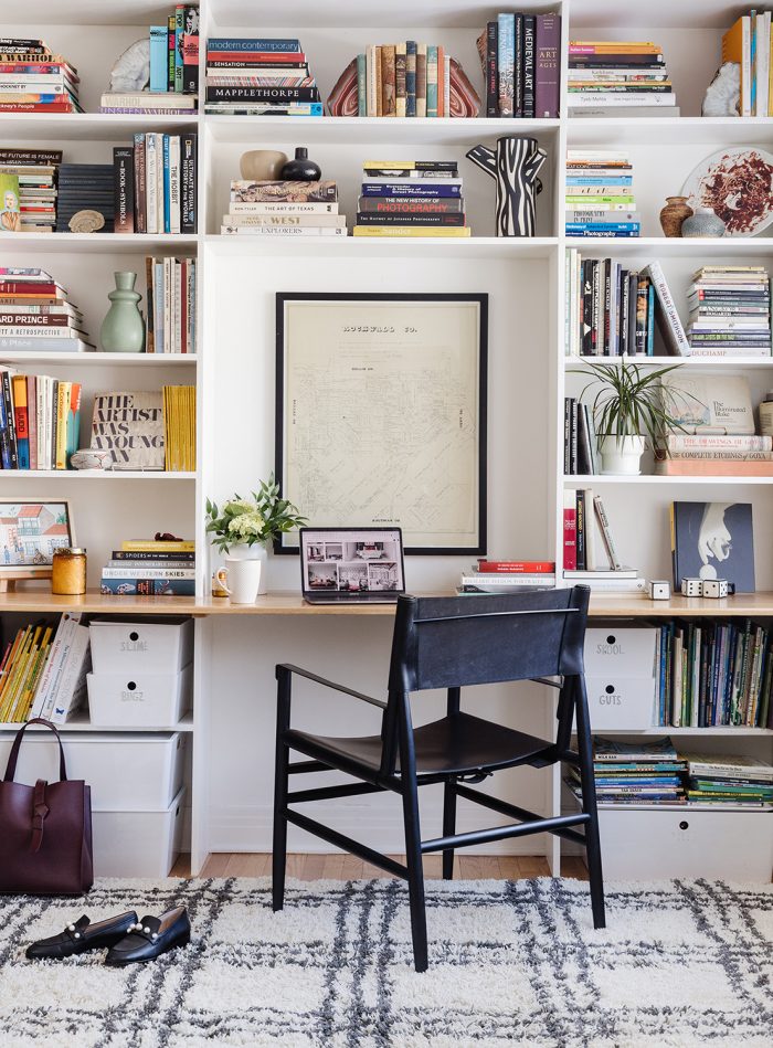 Estante de livros, decorada com plantas, objetos decorativos e espaço para área de trabalho