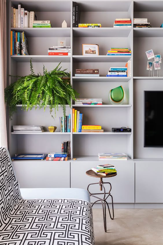 Estante cinza decorada com livros, porta retrato, plantas e objetos decorativos