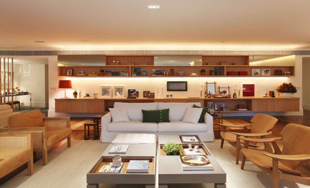 SALA AMPLA, COM ESTANTE DECORADA, MUITA MADEIRA E SOFÁ CLARO