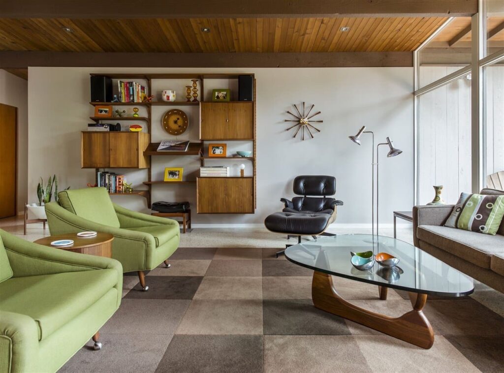 SALA ESTILO RETRÔ COM POLTRONAS VERDES, E PRETA, ESTANTE EM MADEIRA E MESA DE CENTRO FORMATO ORGANICO
