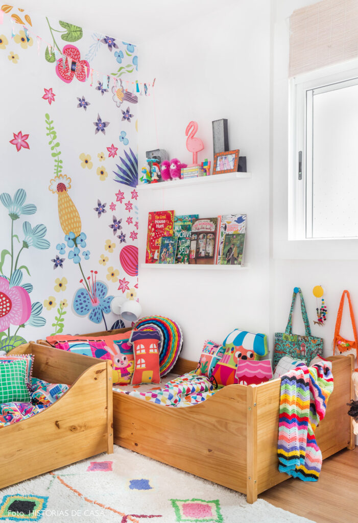 QUARTO DE BEBE COM MINI CAMAS, PAPEL DE PAREDE COLORIDO FLORAL E ROUPA DE CAMA ESTAMPADA