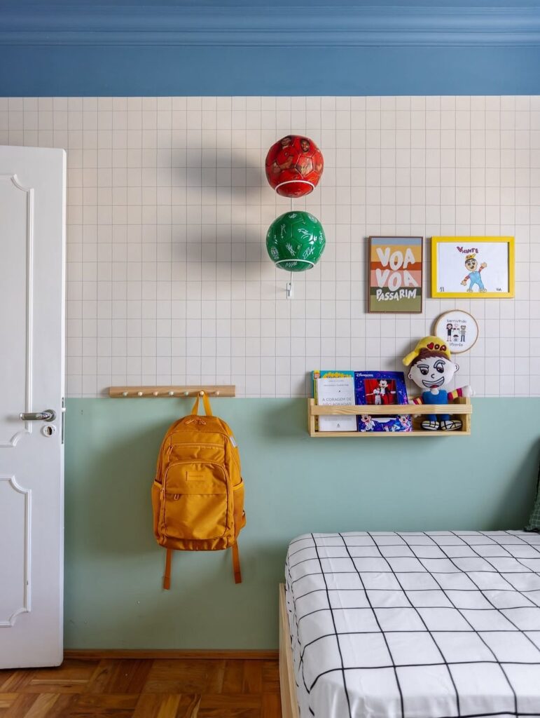 QUARTO DECORADO COM MEIA PAREDE VERDE, PAPEL DE PAREDE, GANCHOS E PRATELEIRA.