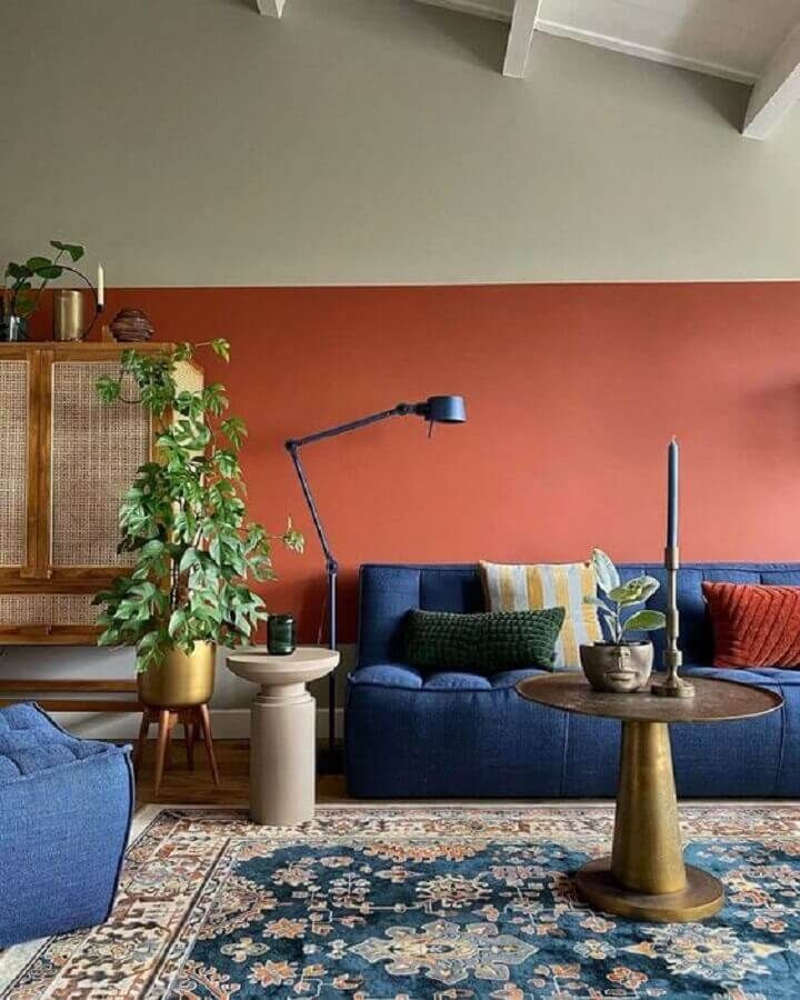 SALA COLORIDA COM SOFÁ AZUL E MEIA PAREDE EM TERRADOTA